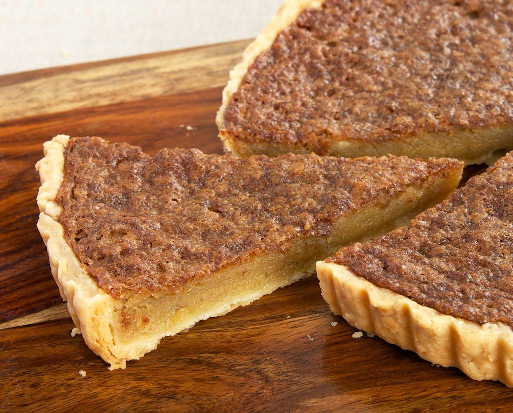 Caramel chess tart on cutting board with one slice cut and pulled away