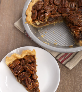 slice of Brown Butter Pecan Pie on a white plate with remaining pie in a pie plate