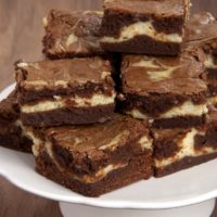 Stack of bourbon cream cheese brownies on white cake stand