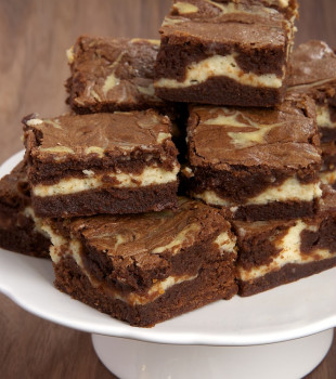 Stack of bourbon cream cheese brownies on white cake stand