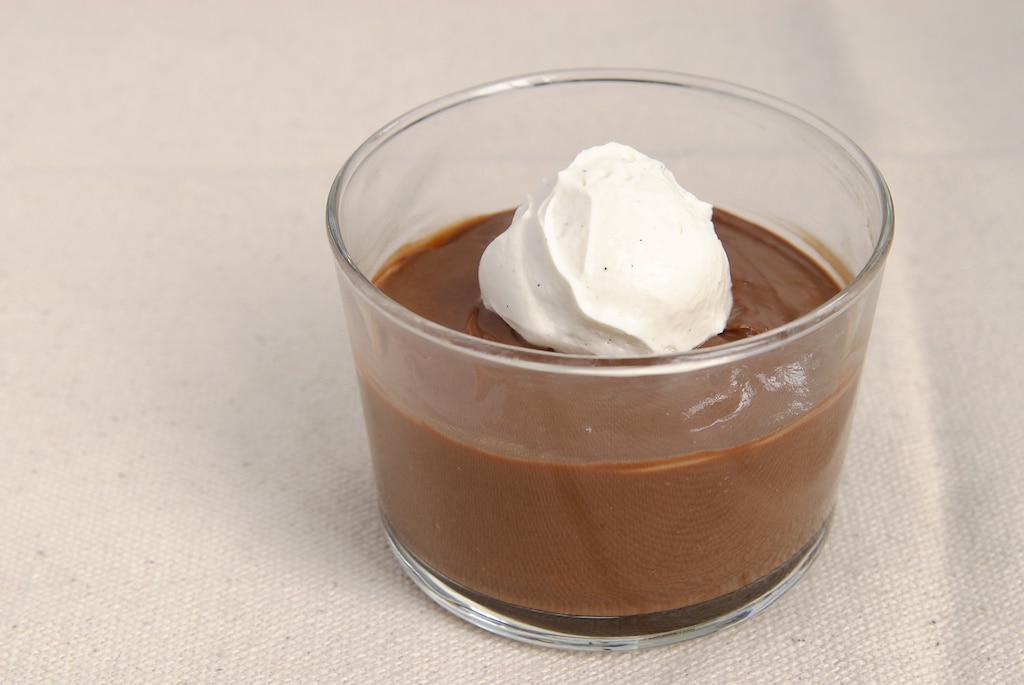 Double Chocolate Pudding topped with sweetened whipped cream and served in a clear glass