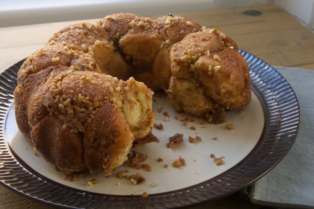 Brown Butter Cinnamon Pecan Pull Apart Bread on serving platter, with pieces removed