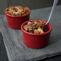 Dark Chocolate Bourbon Bread Puddings in red ramekins on a dark gray surface