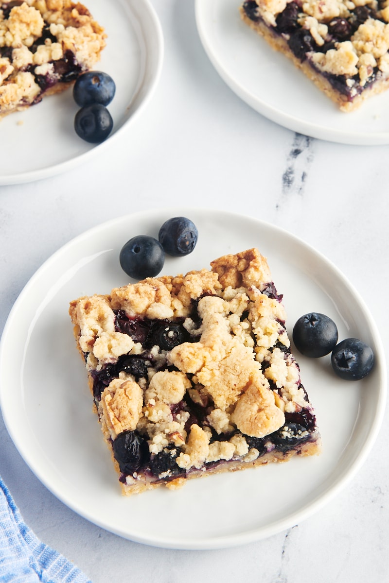 Blueberry pie bar on a plate with fresh blueberries.
