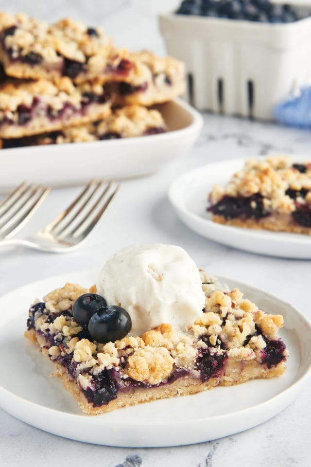 A blueberry bar with vanilla ice cream on a plate.