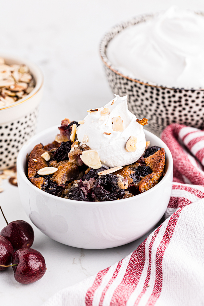 White bowl with brown butter cherry cobbler and dollop of whipped cream