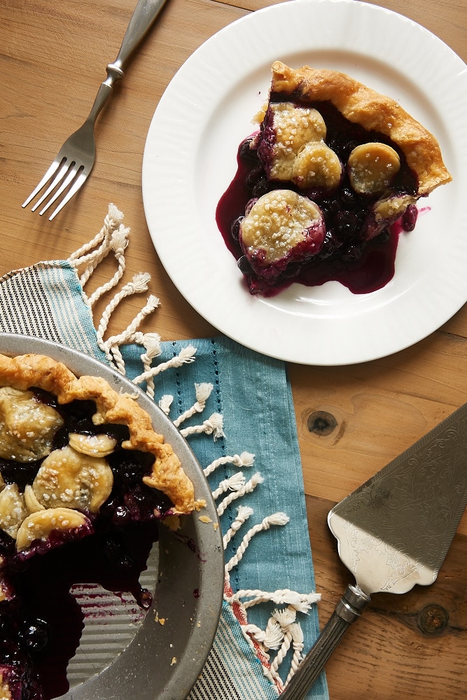 Overhead view of a slice of Blueberry Ginger Pie on a white plate.