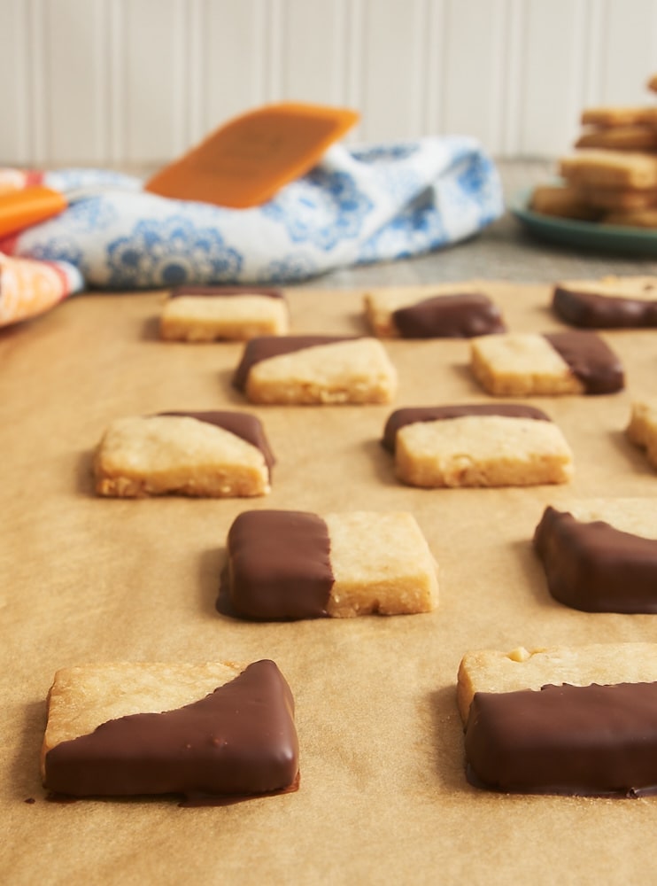 Chocolate-dipped hazelnut shortbread cookies on parchment paper.