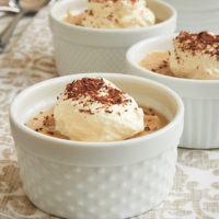 Peanut Butter Pudding served in white ramekins and topped with sweetened whipped cream and cocoa powder