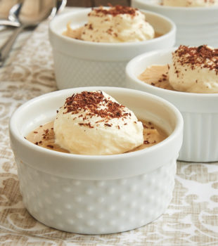 Peanut Butter Pudding served in white ramekins and topped with sweetened whipped cream and cocoa powder