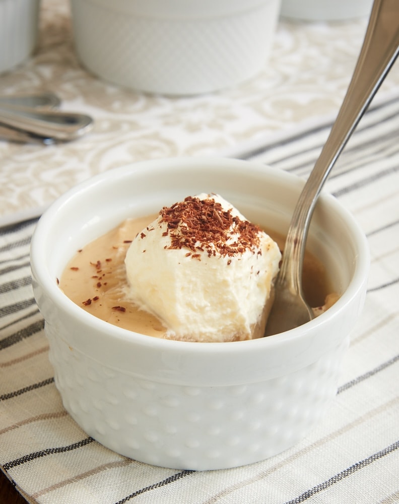 a white ramekin filled with Peanut Butter Pudding with a spoon in the ramekin where a bite is missing