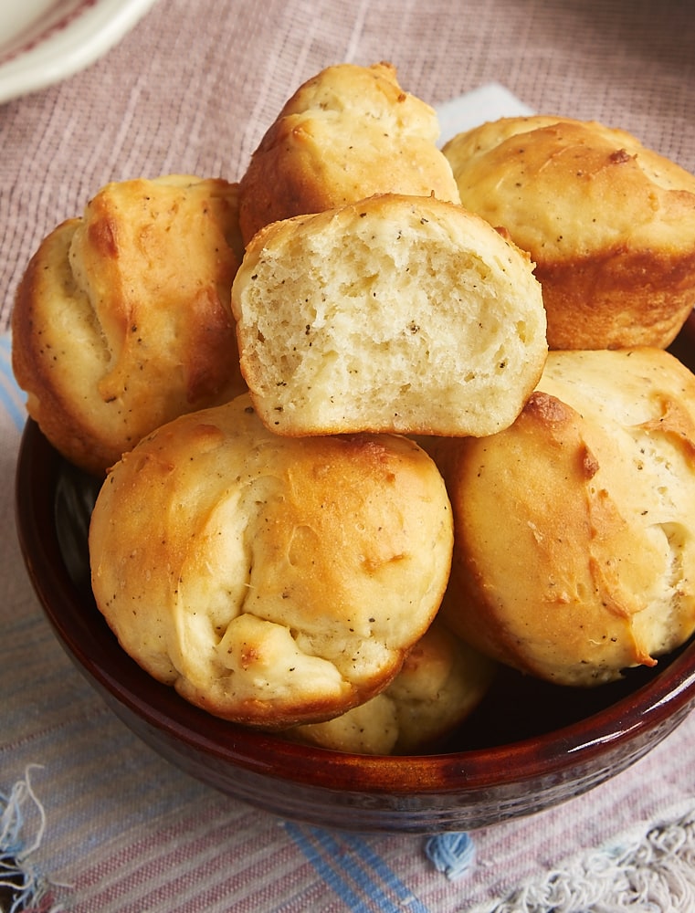 Cracked Pepper Sour Cream Rolls in a brown bowl with half of a roll on top