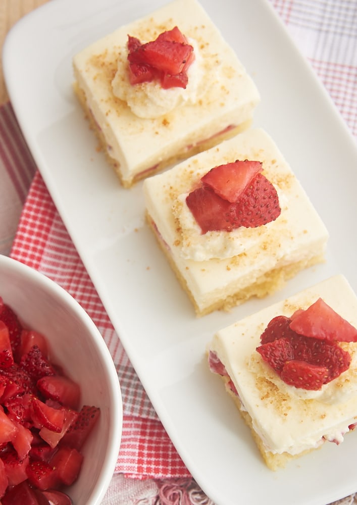 overhead view of three slices of Strawberry Shortcake Cheesecake Bars on a rectangular white plate