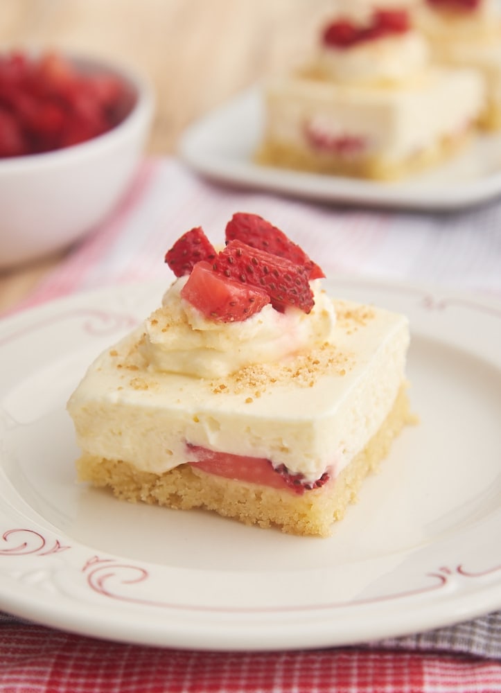 Strawberry Shortcake Cheesecake Bars on a white plate with a red decorative design around the outside