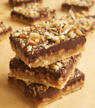 Stack of Butter Pecan Turtle Bars on parchment paper.