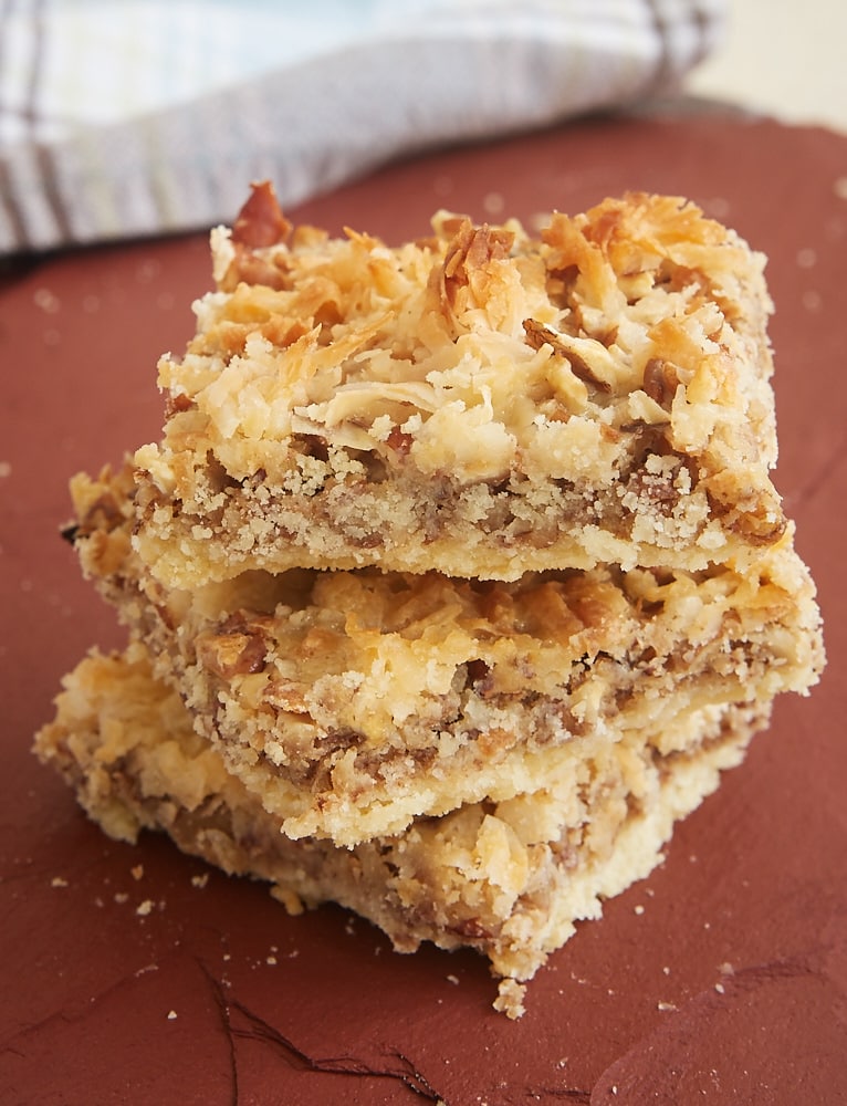 Stack of coconut pecan shortbread bars on a cutting board.