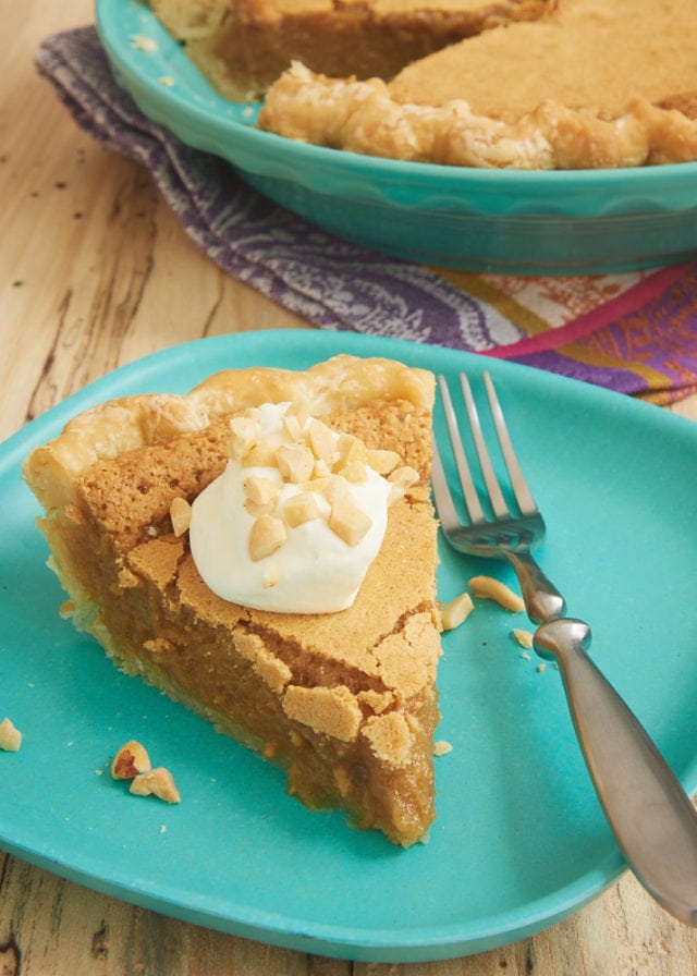 slice of Peanut Butter Chess Pie topped with sweetened whipped cream and served on a green plate