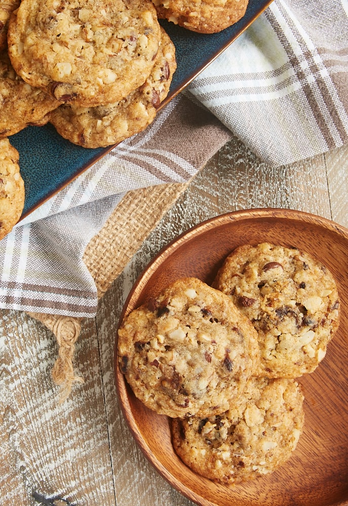 overhead view of Chocolate Chip Date Nut Cookies on a round wooden plate and a blue tray