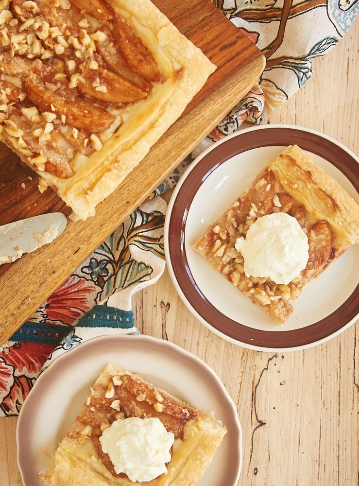 slices of Cream Cheese-Filled Pear Tart topped with sweetened whipped cream