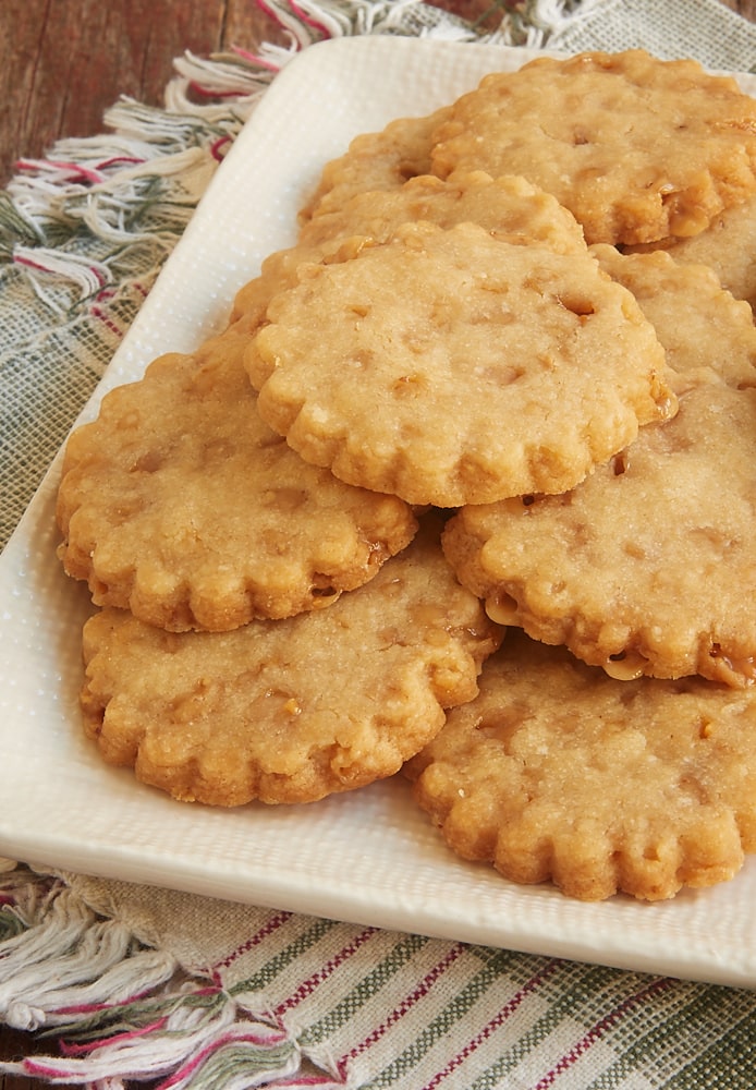 A textured white plate piled with brown sugar toffee shortbread cookies.