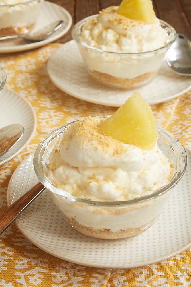 No-Bake Pineapple Cheesecakes topped with whipped cream and pineapple wedges