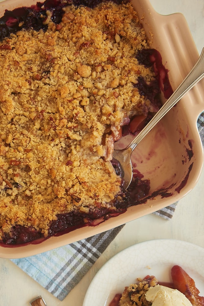 Blueberry Peach Crisp in square baking dish with serving spoon