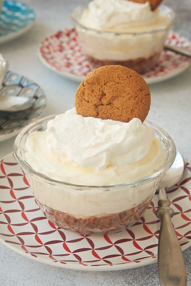 No-Bake Lemon Cheesecakes topped with sweetened whipped cream and gingersnaps