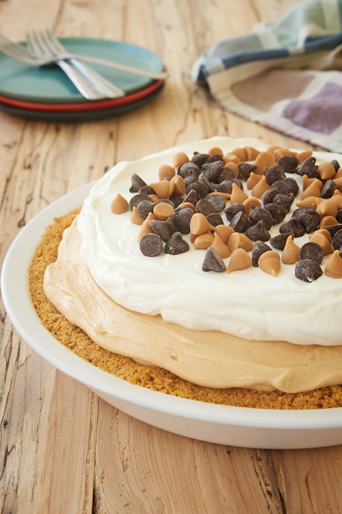 Black Bottom Peanut Butter Pie topped with sweetened whipped cream, peanut butter chips, and chocolate chips