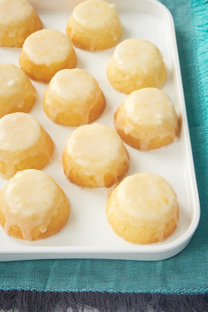 A white tray of Mini Lemon Pound Cakes set atop a turquoise tablecloth