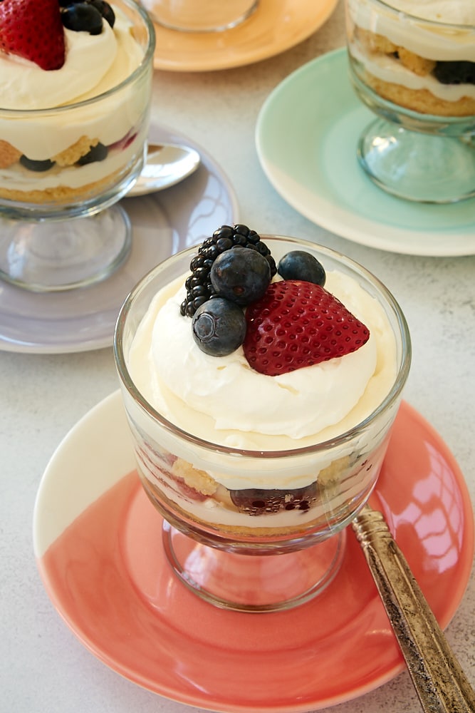 Individual Berry Cheesecake Trifles served in mini trifle bowls on multi-colored plates