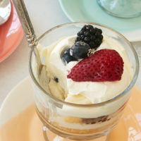 a Berry Cheesecake Trifle with a bite missing and a spoon inside the glass