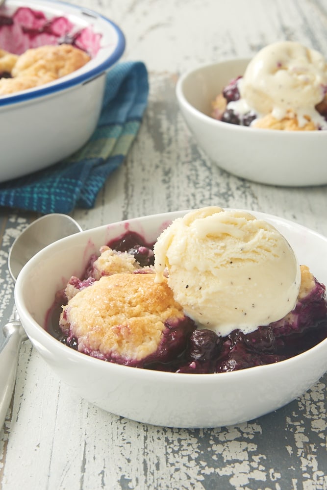 Blueberry Cobbler with Ginger Biscuits topped with ice cream and served in a white bowl
