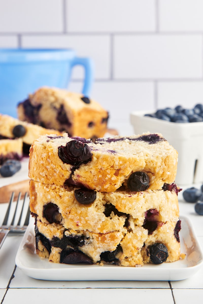 Blueberry loaf slices stacked on a plate.