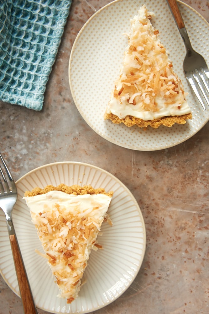 two slices of No-Bake Coconut Cheesecake on white and beige plates