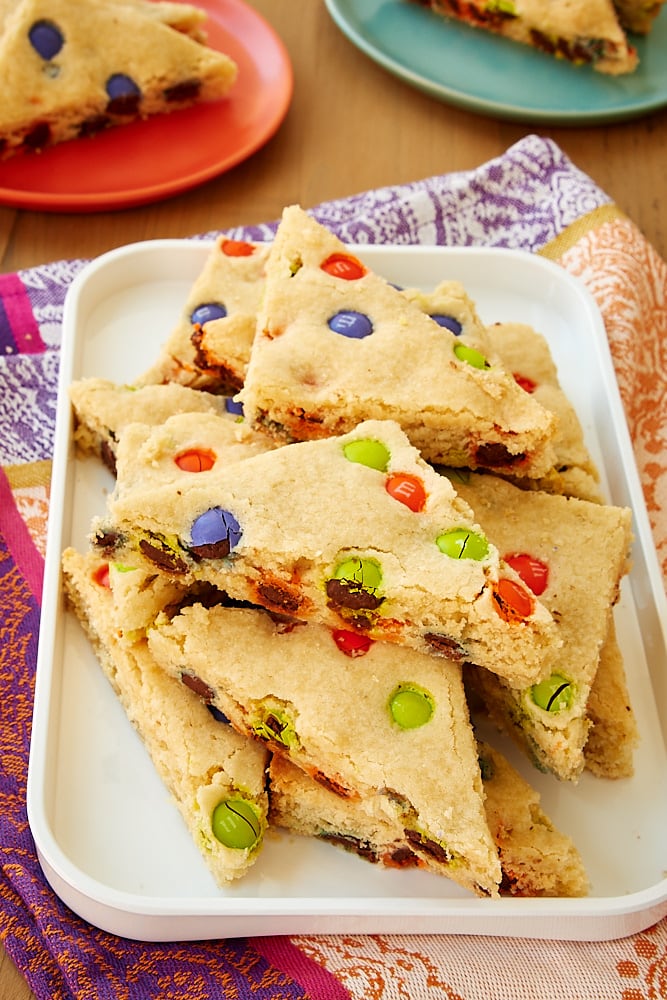 M&M sugar cookie bars stacked on a white tray.