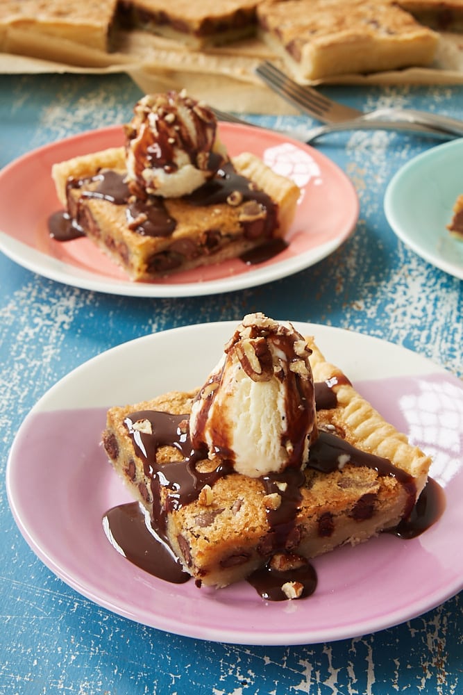 skivor av Double Chocolate Chip Slab Pie toppad med glass, choklad sirap och nötter