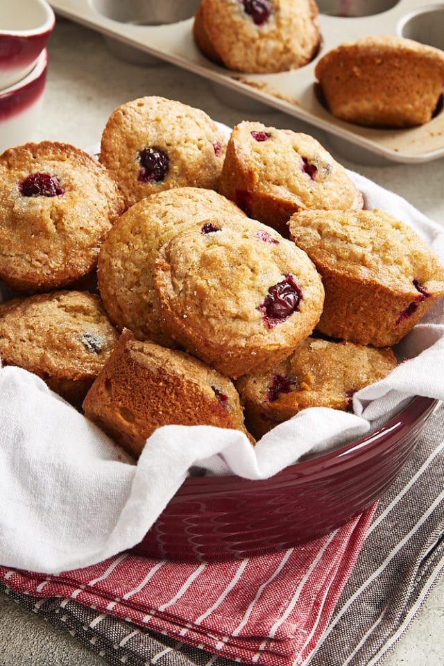 Cranberry Orange Muffins piled in a napkin-lined red bowl