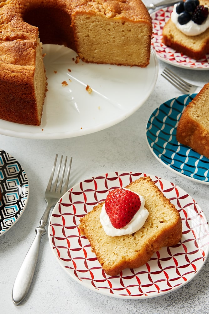 Sour Cream Pound Cake on a white cake stand with slices of cake around it