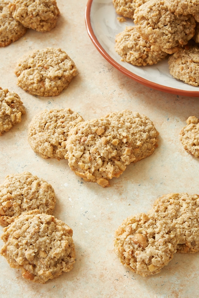 Salted Cashew Crunch Cookies scattered on a light beige surface