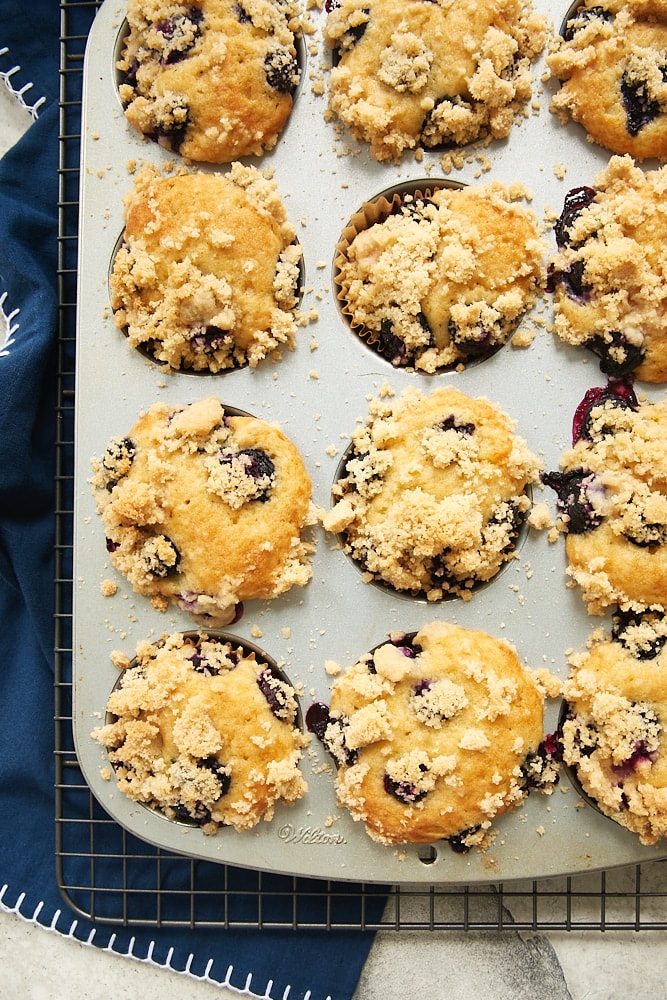 overhead view of Blueberry Coffee Cake Muffins in a muffin pan on a wire rack