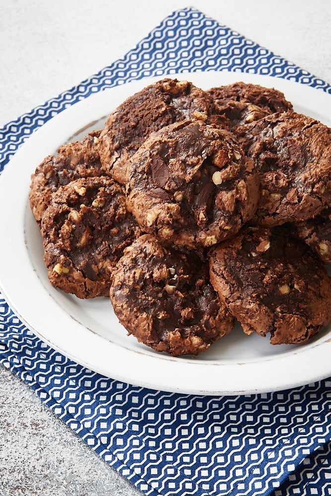 Flourless Chocolate Hazelnut Cookies piled on a white plate on a blue and white napkin