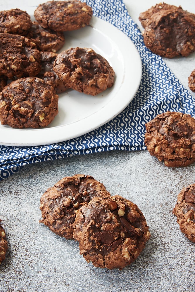 several Flourless Chocolate Hazelnut Cookies scattered on a gray surface