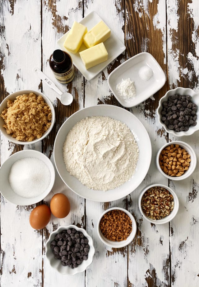 ingredients for chocolate chip cookie bars, including flour, butter, brown sugar, and various add-ins