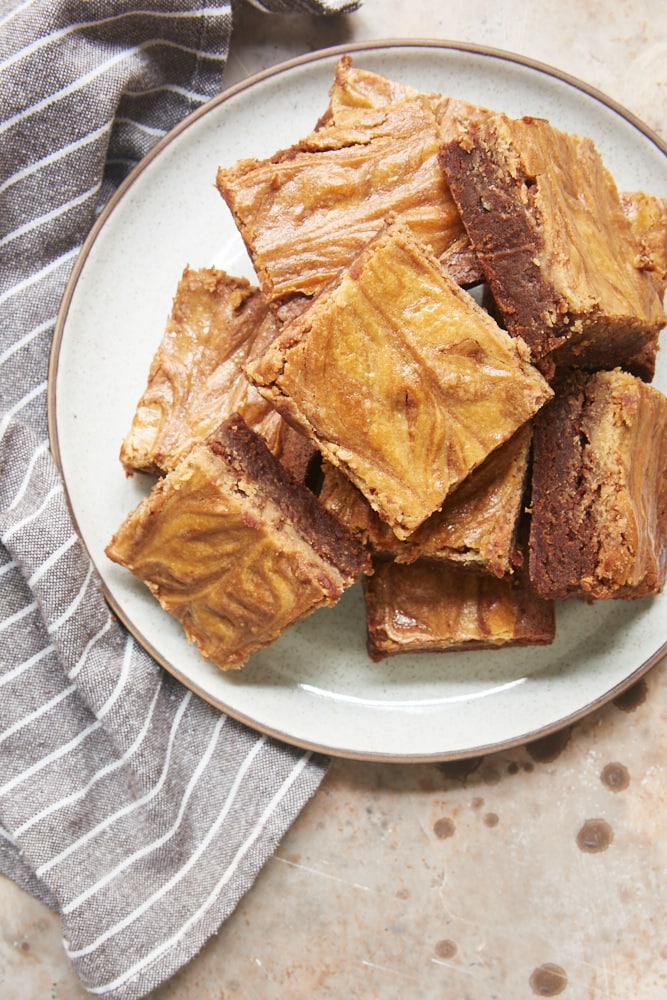 overhead view of Cookie Butter Cheesecake Brownies on a white and brown speckled plate