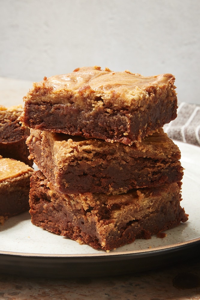 Stack of 3 cookie butter cheesecake brownies on a plate