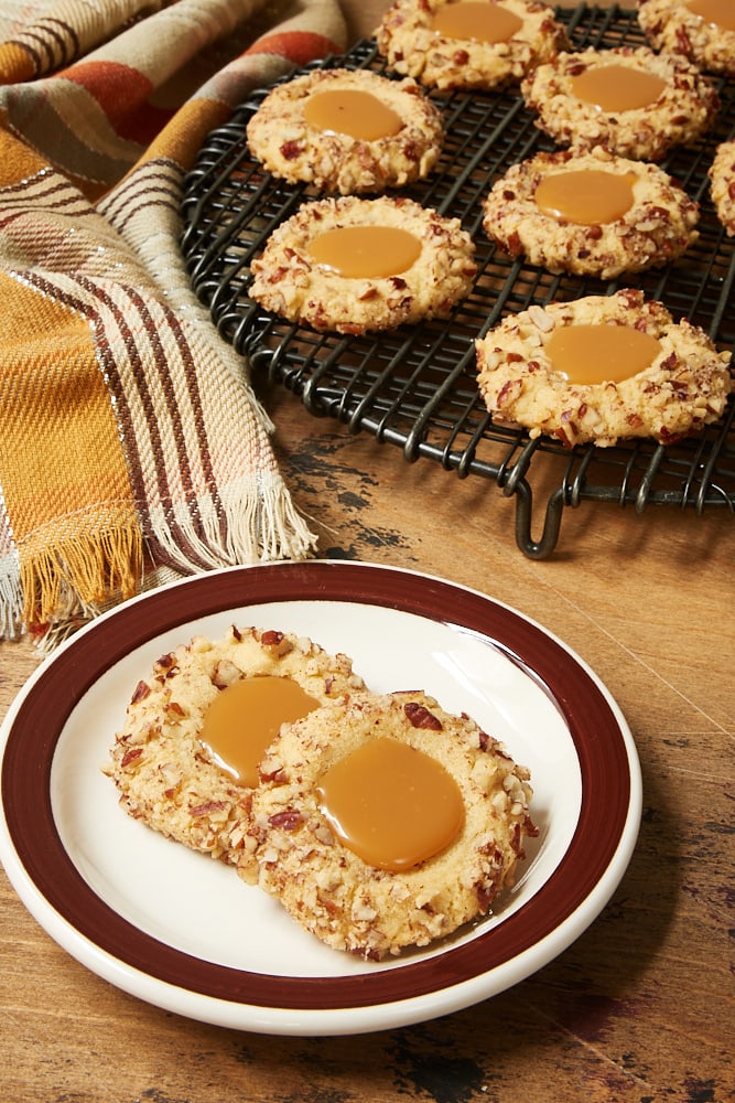 Caramel Pecan Thumbprint Cookies on a brown-rimmed white plate