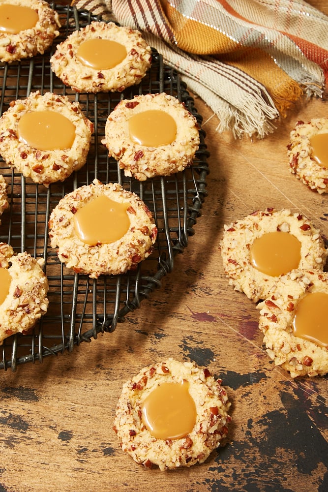 Caramel Pecan Thumbprint Cookies on a wire rack and a wooden surface