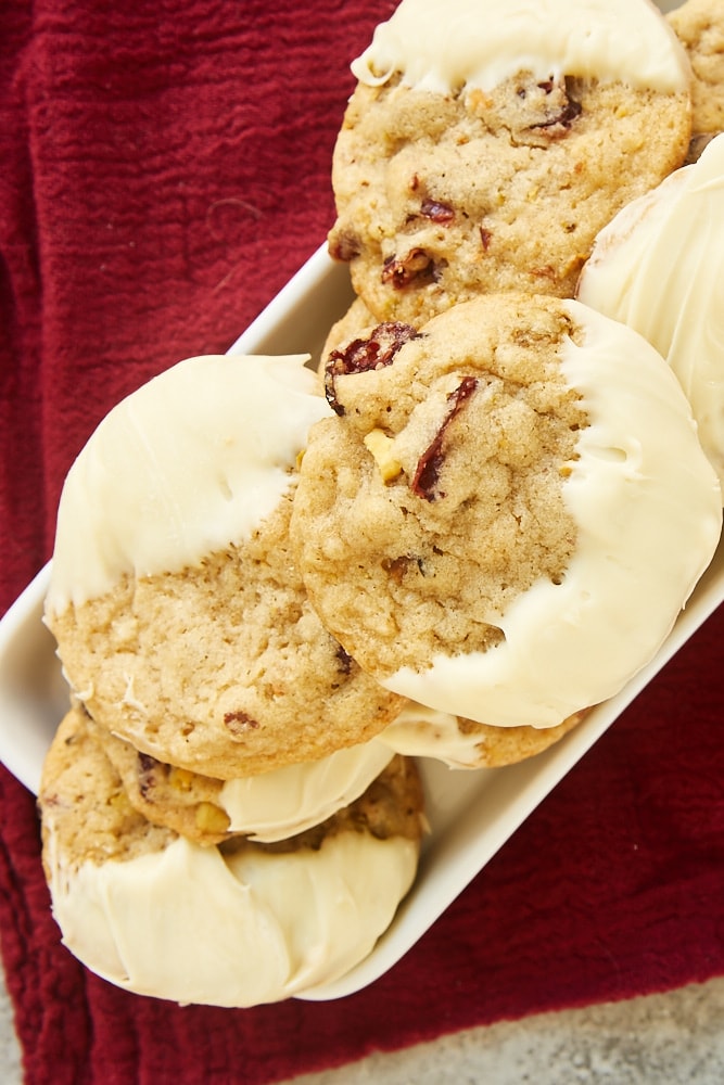 overhead view of Cranberry Pistachio Cookies on a small white tray on a dark red fabric