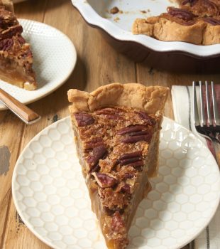 slice of Irish Cream Pecan Pie on a white and beige plate