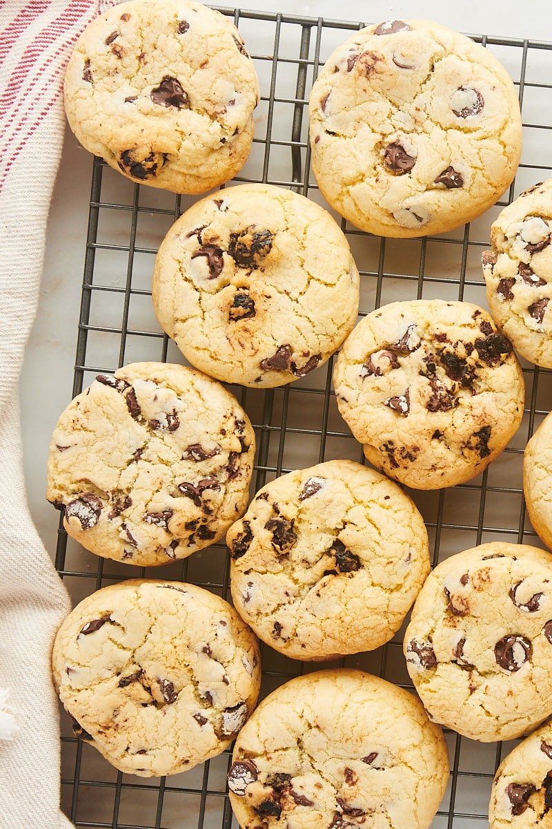Cookies with cherries and chocolate chips cooling on a rack.